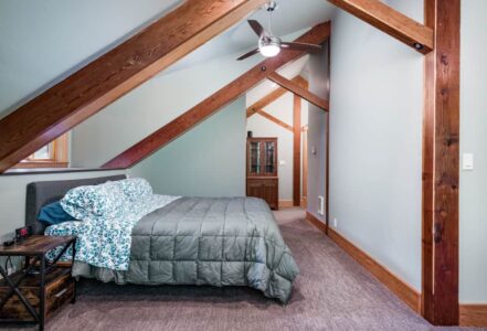 King bed with blue floral bedding in an a-frame attic.