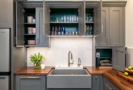 Elevated stone base kitchen sink nested under a wooden countertop.