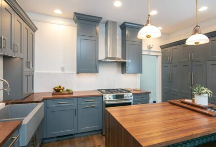 Wood island in the middle of a kitchen with hanging lights above.