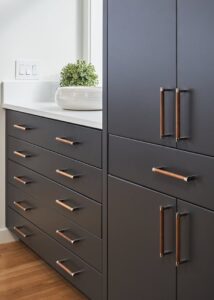 Dark kitchen cabinets with brass pull handles.