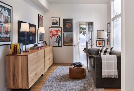 Remodeled den with a wooden dresser, wall art, and a couch.