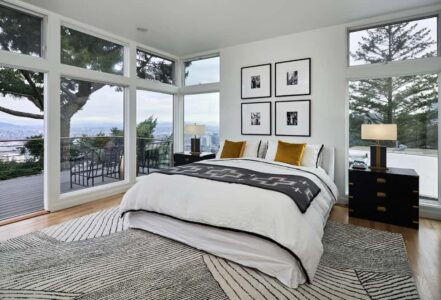 Four hanging pieces of wall art above a king bed with a white duvet.
