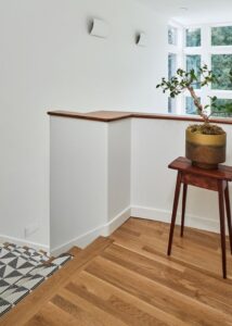 Hallway at the top of the stairs with a small table with a potted plant on top.