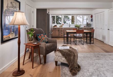 Chair with a wooden side table and foot rest in a home entry way.