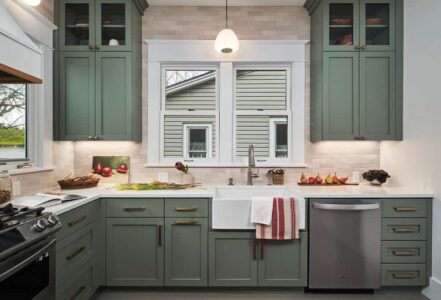 Porcelain farmhouse apron sink with Signature Hardware faucet below two kitchen windows.