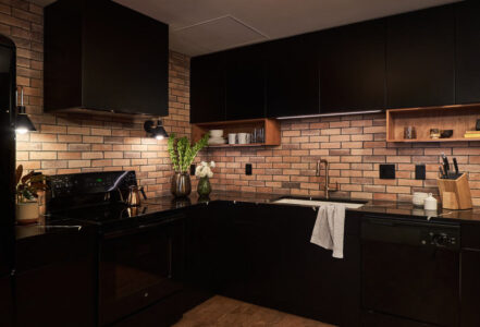 Transitional industrial condo kitchen with black appliance, a black countertop, and Arto brick backsplash from Tempest Tile.