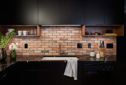 Undermount white porcelain sink with Brizo faucet in a black countertop.