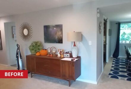 Hallway sideboard against the wall with ceramics and a lamp on top, below a painting.