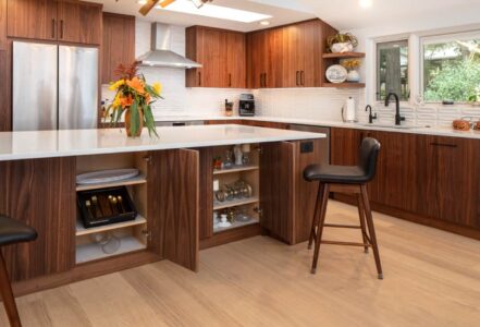 Kitchen island with waterfall countertop and medium-dark wood grain cabinetry from Decor Cabinets.