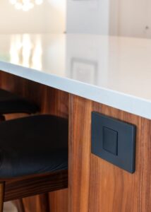 Closed black cover pop-out electrical outlet in a kitchen countertop.