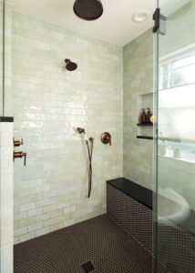 Large shower with Trinity Surfaces ceramic shower tile in “Mist” and Daltile black penny tile.