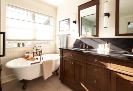 Crystal Cabinet Works custom vanity made with quarter-sawn white oak stained “Sepia” nezt to a clawfoot tub.