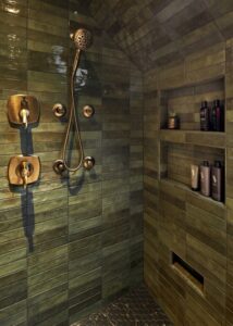 Shower head in a separate shower with built in wall shelves.