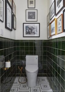 Toilet in a transitional bathroom with green tile and mosaic marble floor.