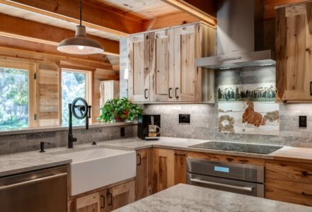 Fully renovated cabin kitchen with stainless steel appliances, a white countertop, and finished wooden cabinets.