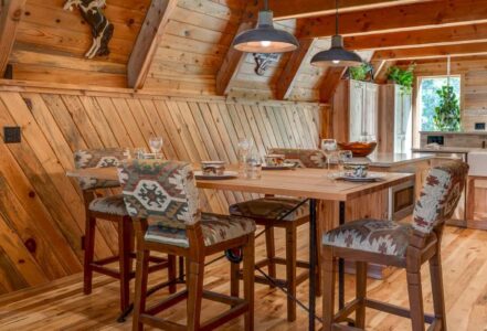 Four-seater high table with four wooden upholstery high-chairs in a cozy cabin home kitchen.