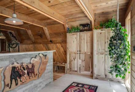 Bright entryway into an A-frame home with a stallion art piece and natural hickory cabinets.