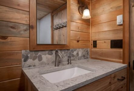 Bathroom vanity with grey granite countertop and a silver faucet.