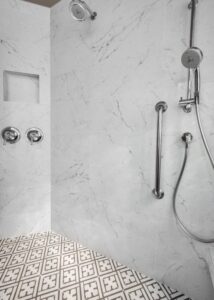 Walk-in shower with a grab bar and a silver shower head.