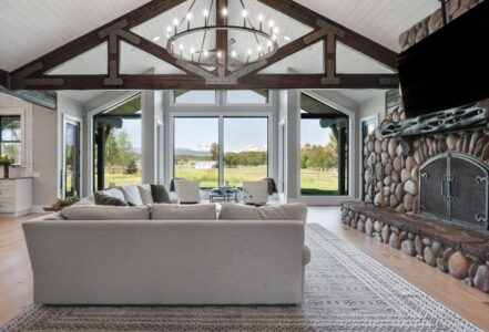 L-Shaped white couch in front of a stone fireplace.