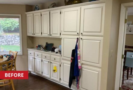 White cabinets with small round pulls built along a kitchen wall.