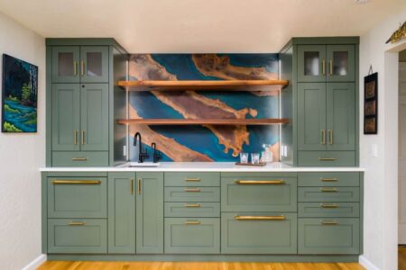 A wet bar with green cabinets and a walnut and blue resin backsplash