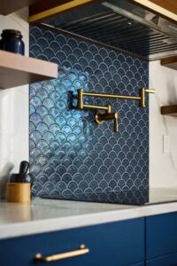 A cooktop backsplash with blue tile and a pot filler