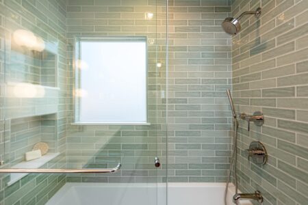 A shower with soft green rectangular tile