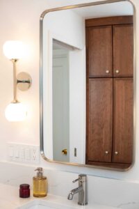 A bathroom mirror with wood cabinets in the reflection