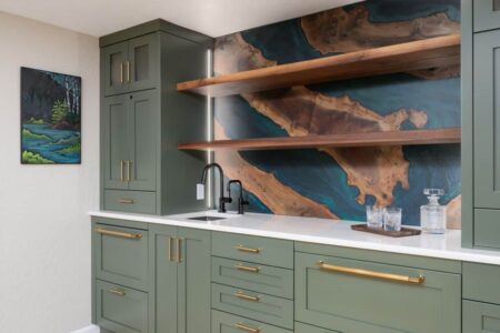 A wet bar with green cabinets and a walnut and blue resin backsplash