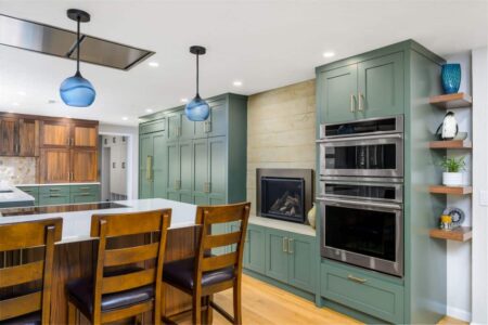 A remodeled kitchen with green cabinets and a fireplace